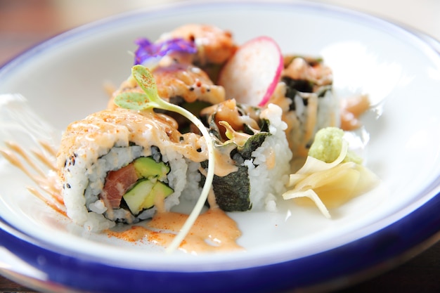 Tonno salmone e avocado uramaki con salsa piccante in primo piano