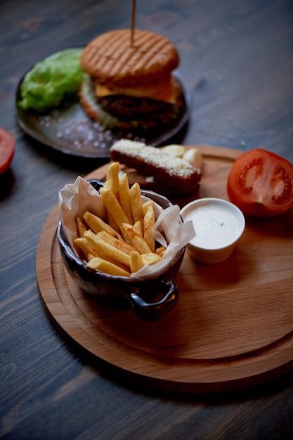 Top in legno sulle sue patatine fritte e BurgerIl concetto di pub e fast food