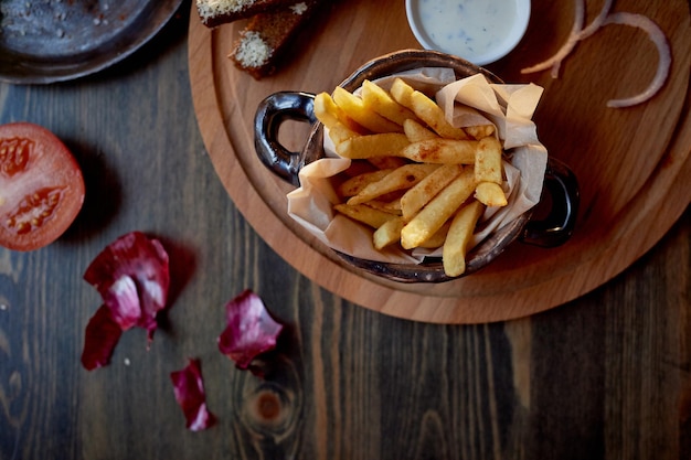 Top in legno sulle sue patatine fritte e BurgerIl concetto di pub e fast food