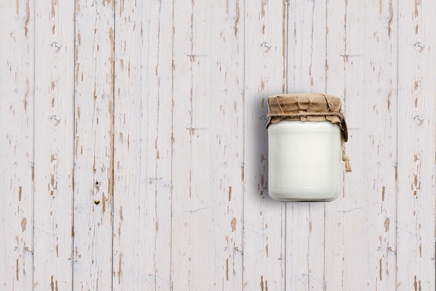 Top up vista barattolo di yogurt isolato su sfondo di legno bianco adatto per il vostro progetto di progettazione