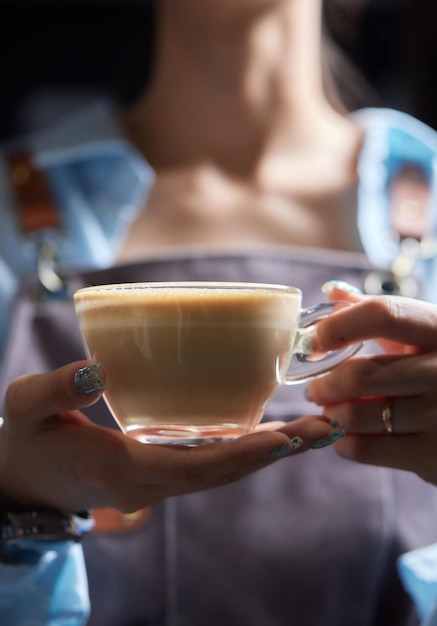 Top view di un barista professionista che versa il latte da un barattolo in una tazza di caffè il caffè che viene preparato da un barista si concentra sulle mani che tengono la tazza di café