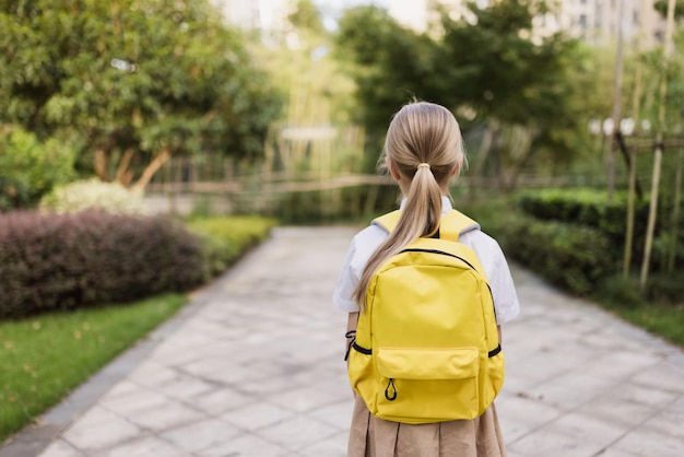 Torna a scuola ragazzina con zaino giallo dalla scuola elementare all'aperto