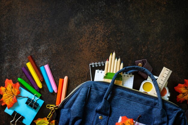 Torna al concetto di scuola Materiale scolastico con zaino blu Vista dall'alto