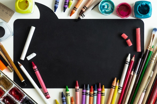 Torna al concetto di scuola. Materiale scolastico su uno sfondo di lavagna. Disteso.