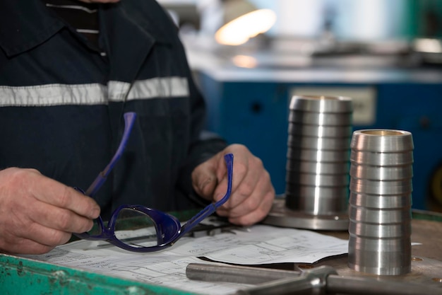 Tornitura o produzione Le mani del lavoratore tengono un giunto di prodotto in metallo