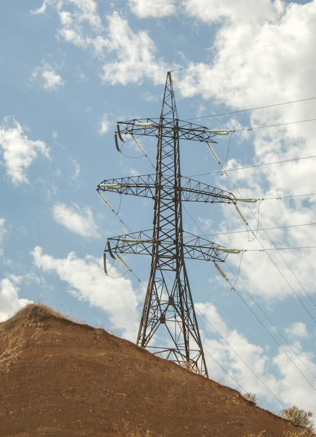 Torre ad alta tensione contro il cielo blu con nuvole