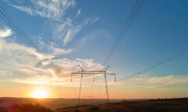 Torre alta tensione con linee elettriche al tramonto Trasmissione di energia elettrica