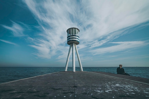 Torre del bagnino e donna con vista sul mare sullo sfondo