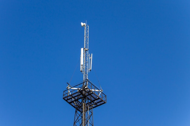 Torre di metallo con antenne per comunicazioni di telefoni cellulari contro il cielo blu