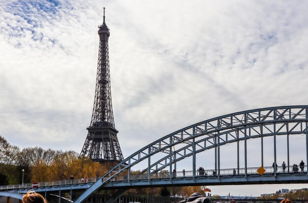 Torre Eiffel contro il cielo blu con nuvole e ponte pedonale passerelle debilly sopra la senna