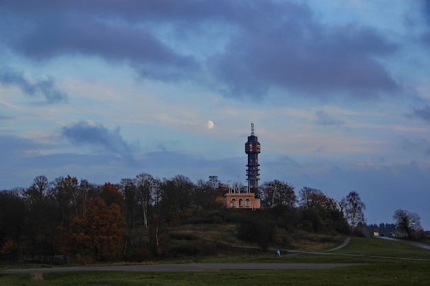 Torre sulla collina al tramonto Foresta d'autunno La luna nel cielo