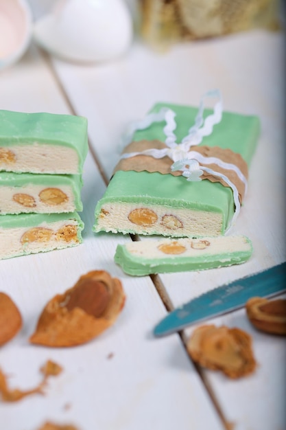 Torrone di mandorle ricoperto di cioccolato al pistacchio su una superficie di legno. Avvicinamento