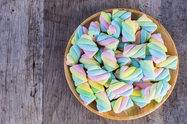 Torsione multicolore della caramella gommosa e molle in un piatto di legno su una tavola di legno.