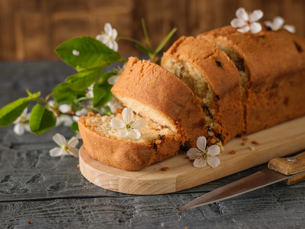 Torta a fette con uvetta e un ramoscello fiorito su un tavolo di legno.