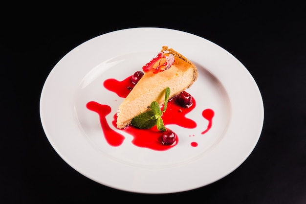 Torta ai frutti di bosco con decorazione su un piatto bianco rotondo su sfondo nero