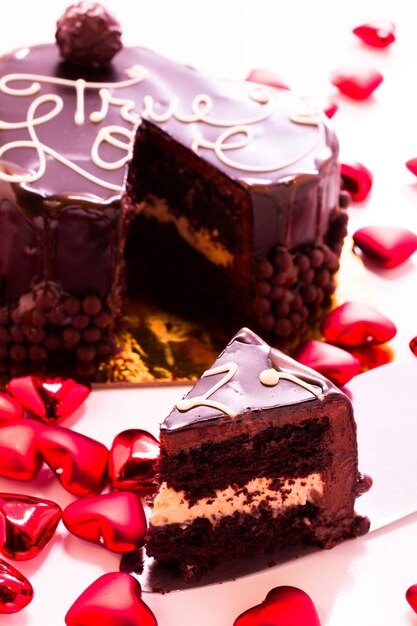 Torta al caramello salato a forma di cuore su sfondo bianco.