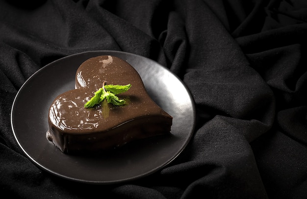 Torta al cioccolato a forma di cuore fatta in casa su sfondo nero