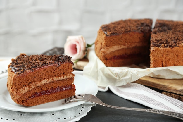 Torta al cioccolato affettata sul piatto sul fondo della tavola in legno