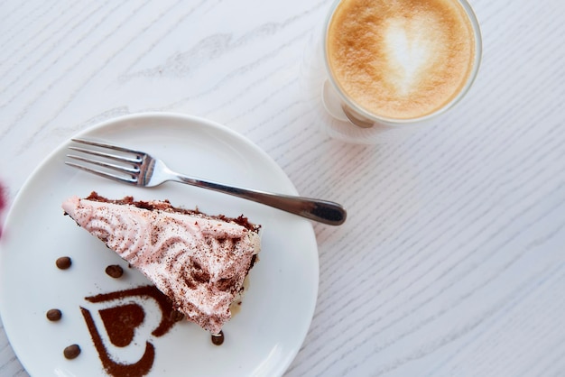 Torta al cioccolato alla frutta e un bicchiere con un doppio fondo di latte su un tavolo di legno all'esterno nella terrazza del bar Colazione suggestiva Decorazioni per dessert a forma di cuore