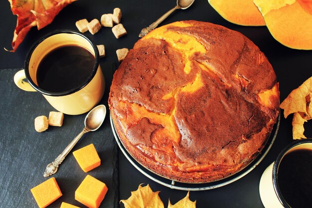 Torta al cioccolato alla zucca su sfondo scuro con vista dall'alto delle foglie autunnali