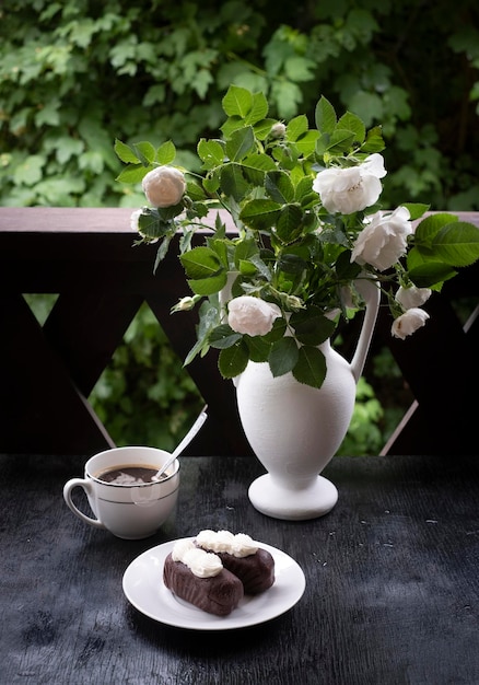 Torta al cioccolato con caffè su un tavolo con rose bianche a casa in veranda
