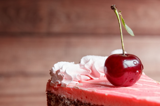 Torta al cioccolato con ciliegie su fondo in legno.