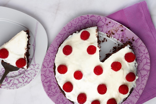 Torta al cioccolato con crema sopra e lamponi