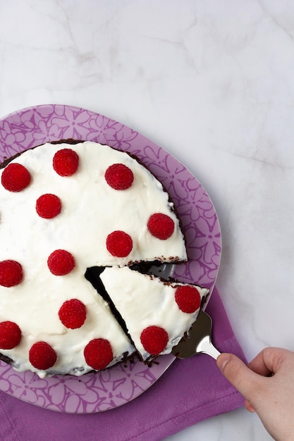 Torta al cioccolato con crema sopra e lamponi