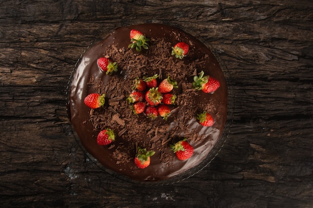 Torta al cioccolato con fragola isolata sulla vista dall'alto della superficie di legno.