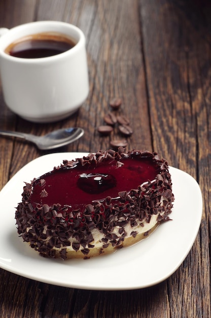 Torta al cioccolato con gelatina di ciliegie e tazza di caffè su tavola in legno rustico