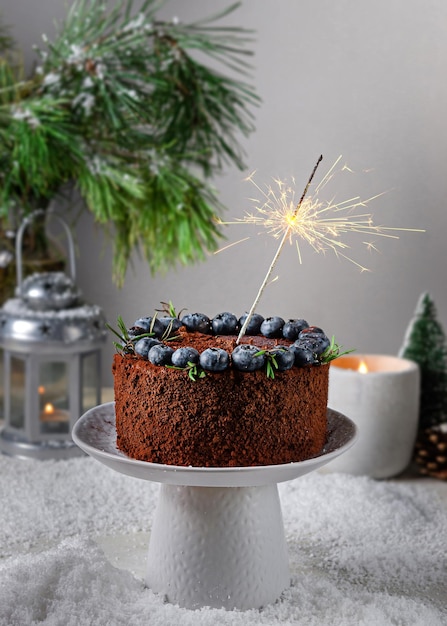 Torta al cioccolato con mirtilli su uno sfondo di neve e un albero di Natale