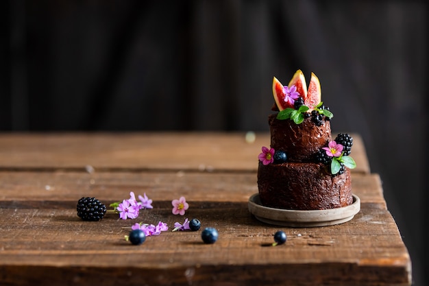 Torta al cioccolato con mora e fichi comuni sul tavolo di legno