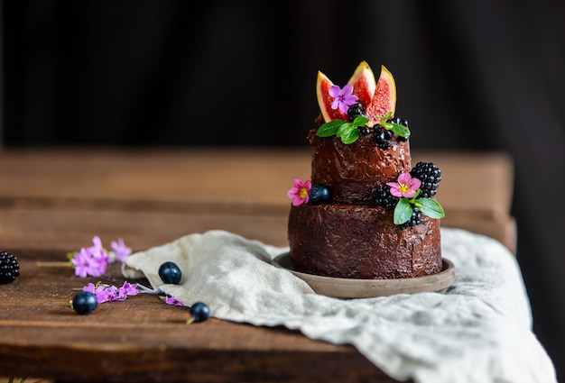 Torta al cioccolato con mora e fichi comuni sul tavolo di legno