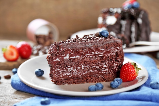 Torta al cioccolato con panna e frutti di bosco freschi sulla piastra su fondo di legno