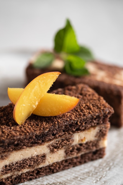 Torta al cioccolato con pesca e menta su uno sfondo chiaro