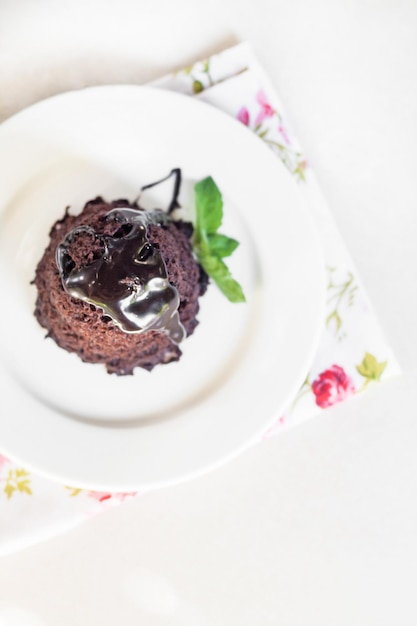 Torta al cioccolato con sciroppo di cioccolato con foglie di menta su un piatto bianco