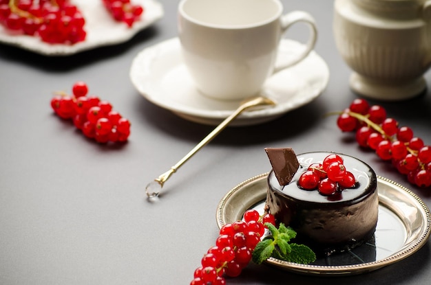 Torta al cioccolato con un ribes rosso su una tazza di piatto e un lattaio