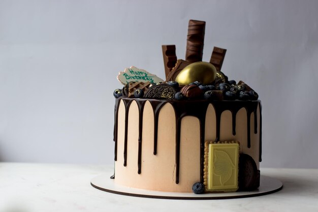 Torta al cioccolato decorata con biscotti e cioccolatini di mirtilli su uno sfondo bianco