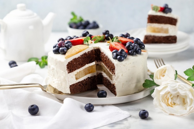 Torta al cioccolato decorata con frutti di bosco freschi su sfondo chiaro Concetto di dolci