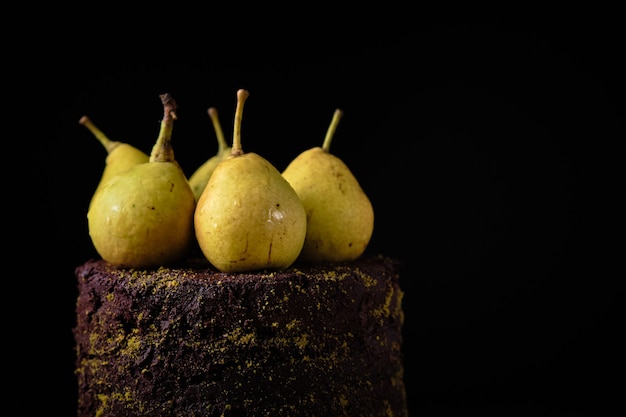 Torta al cioccolato decorata con pistacchi macinati e pere fresche su tavola di legno.