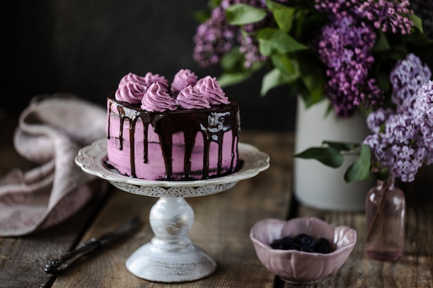 Torta al cioccolato e un mazzo di lillà sul tavolo di legno