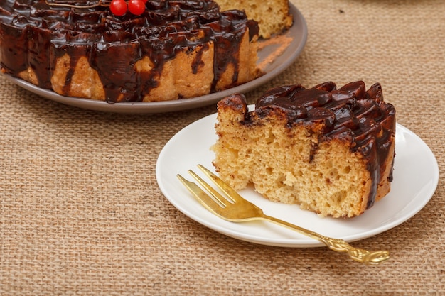 Torta al cioccolato e una fetta sul piatto con la forchetta, sul tavolo con la tela di sacco.