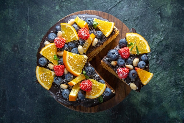 Torta al cioccolato gustosa vista dall'alto con frutta su fondo scuro