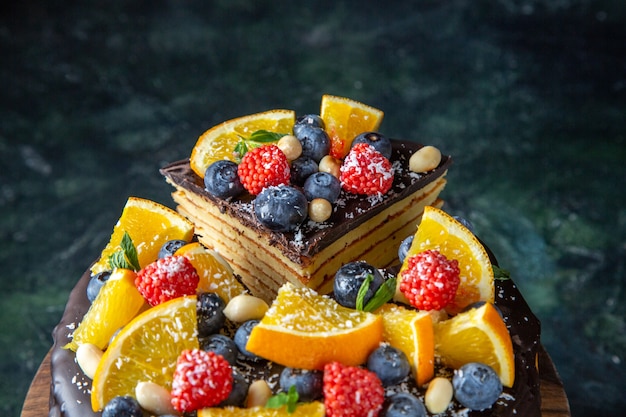 Torta al cioccolato gustosa vista frontale con frutta sulla parete scura