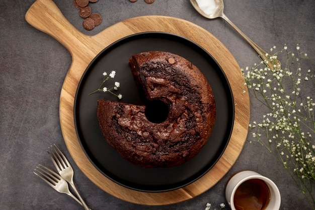 Torta al cioccolato su una banda nera e un supporto in legno su uno sfondo grigio