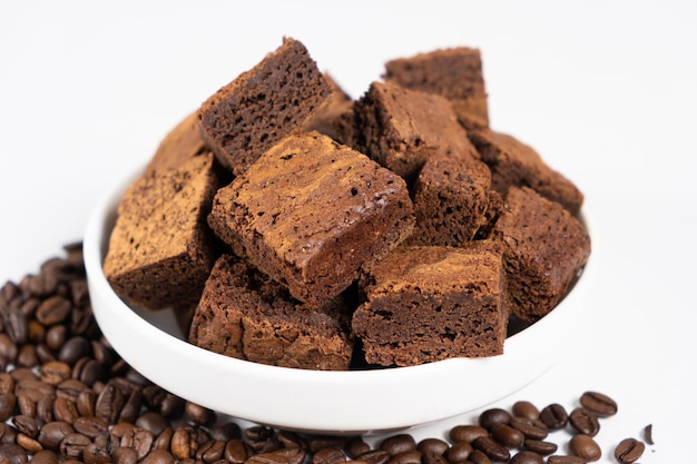 Torta al cioccolato tagliata a quadratini in un piatto bianco brownie e chicchi di caffè