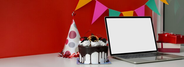 Torta al cioccolato vicino al computer portatile con lo schermo in bianco