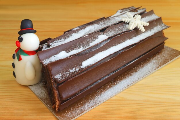 Torta al cioccolato Yule Log con un simpatico pupazzo di neve di marzapane per le feste di Natale