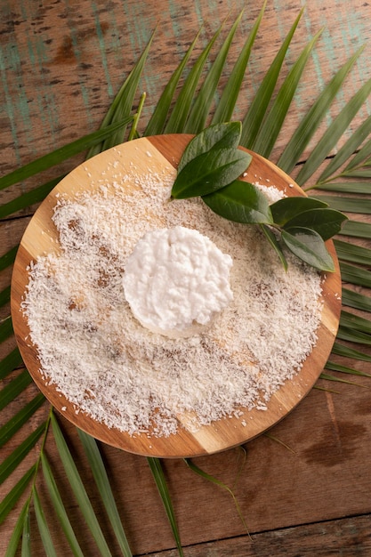 Torta al cocco con glassa e cocco sminuzzato su tavola di legno su tavolo rustico tropicale in vista dall'alto