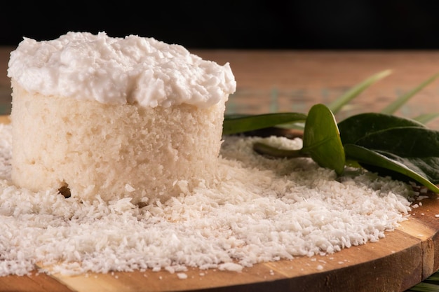 Torta al cocco con glassa e cocco sminuzzato su tavola di legno sul primo piano tavolo rustico